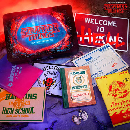 Collection of 'Stranger Things' themed items including a laptop, signs, and memorabilia on a dark surface with red lighting.